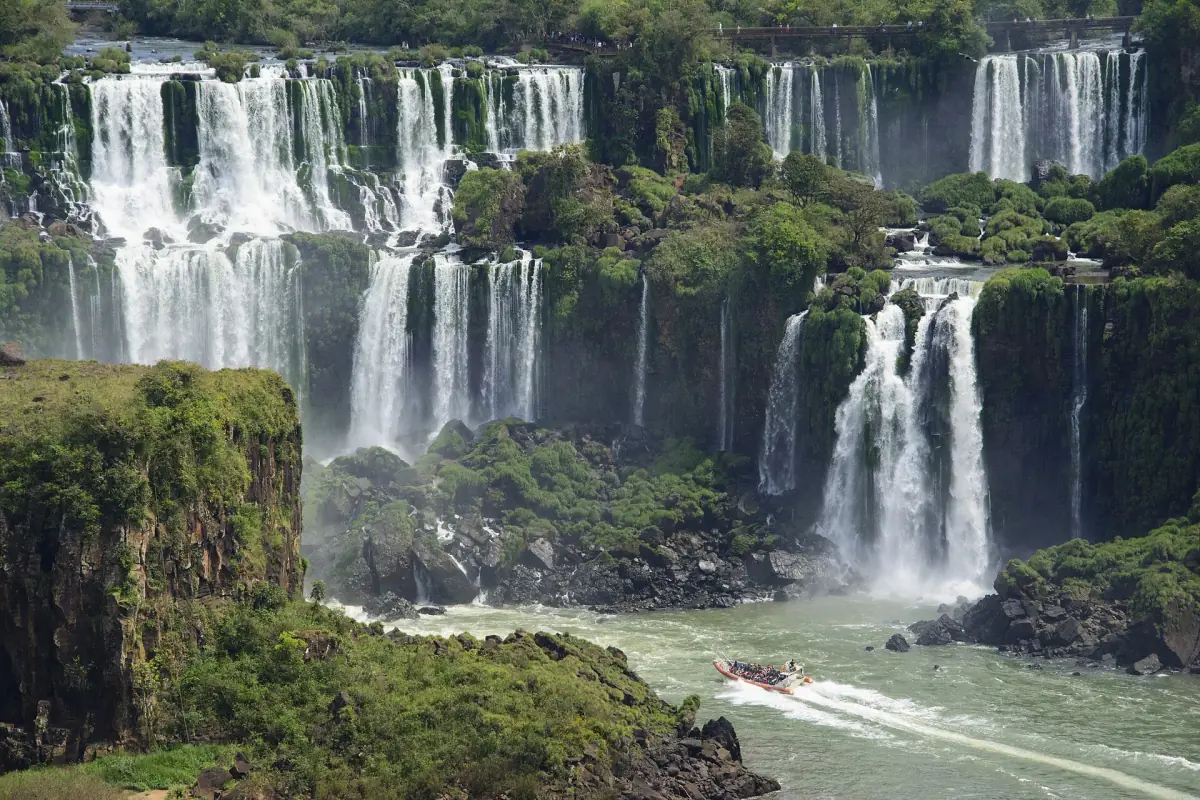 A boat on the river below cascading waterfalls