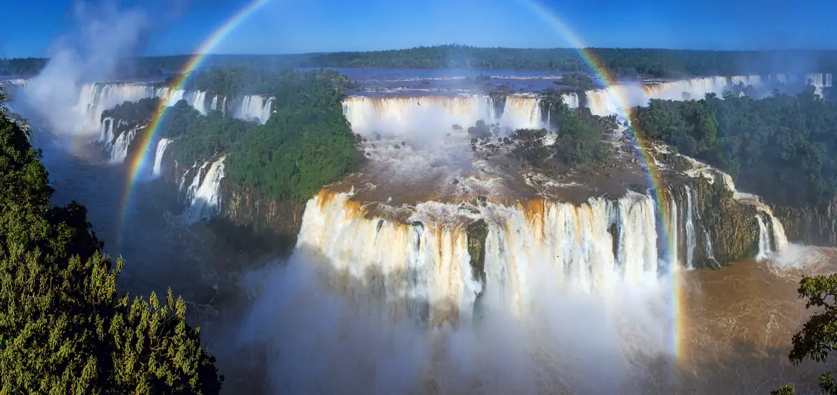 Aerial panorama of Iguazu Falls with a rainbow over the gorge