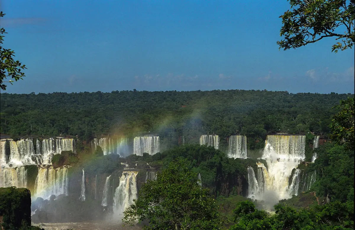 Several waterfalls of Iguazu with a rainbow above the forest
